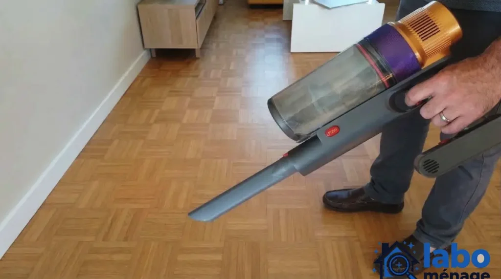 Utilisation de l’embout long pour aspirer au ras du sol près d’un meuble.