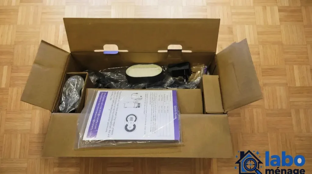 Carton ouvert avec les différents éléments du produit et le manuel visibles à l’intérieur.